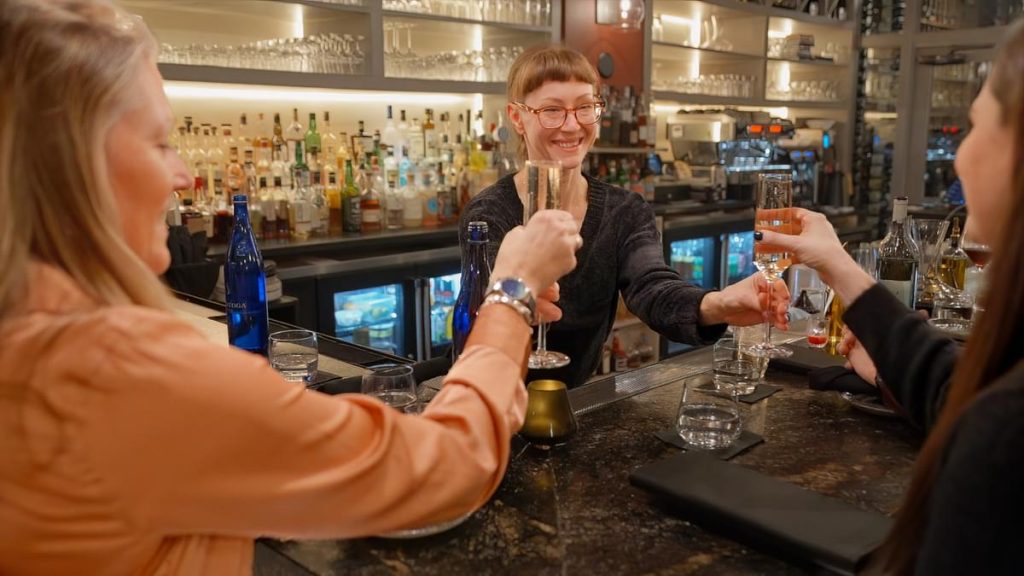 Bartender serving champagne to two besties