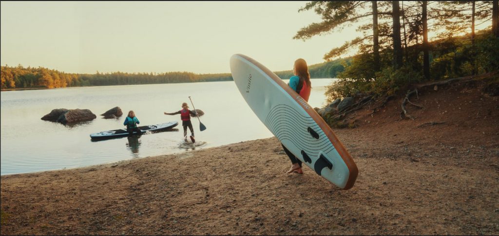Mother and two kids at the beach with paddle boards