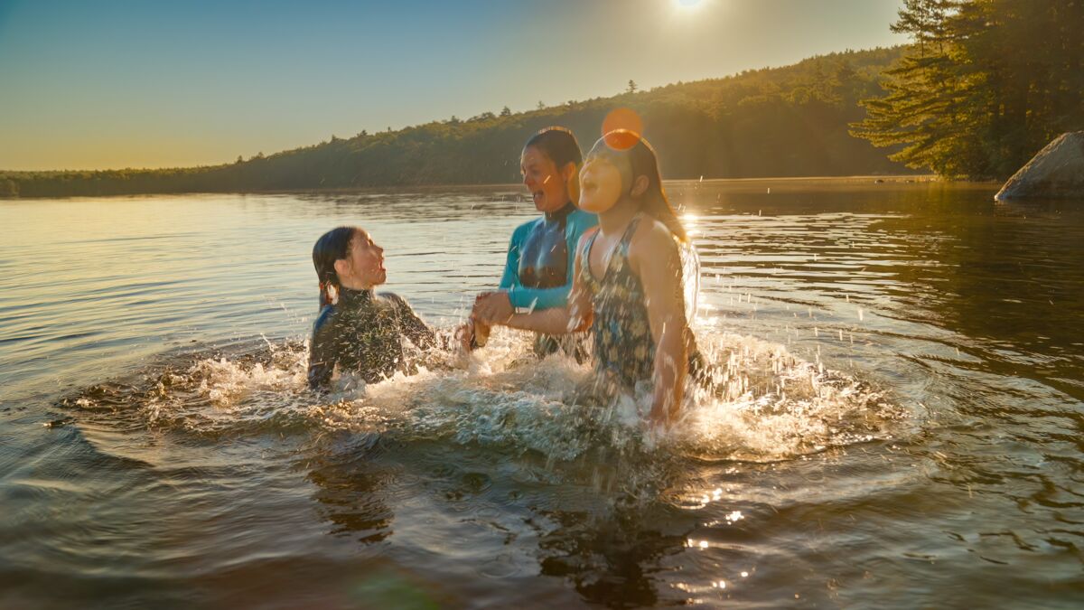 A mom and her two kids splashing in a lake 