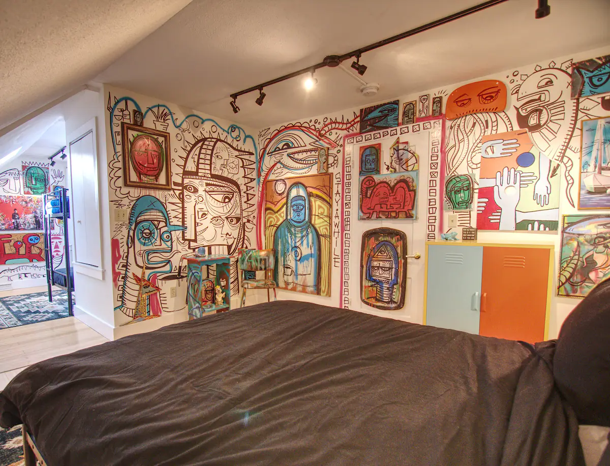 An Airbnb bedroom with colorful murals on the wall